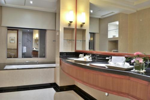 a bathroom with two sinks and a large mirror at Rama Gardens Hotel Bangkok in Bangkok