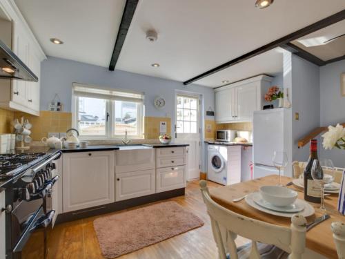 cocina con armarios blancos y mesa de madera en Holiday Home Spop by Interhome en Wadebridge