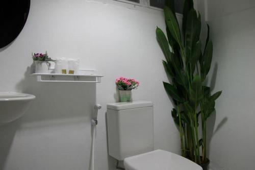 a white bathroom with a toilet and a plant at Baantalaywhan Resort in Ban Huai Yang