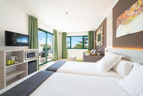 a hotel room with a large bed and a television at Apartamentos Galeon Playa in Costa Teguise