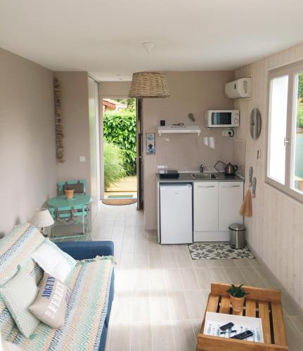 une cuisine et un salon avec un canapé et une table dans l'établissement PETIT STUDIO de L'ERMITAGE, à Gujan-Mestras