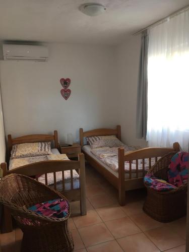 1 Schlafzimmer mit 2 Betten, 2 Stühlen und einem Fenster in der Unterkunft Apartments 4M in Gornji Karin