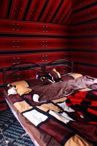 a bed in a room with a red wall at Wadirum sunrise camp in Wadi Rum