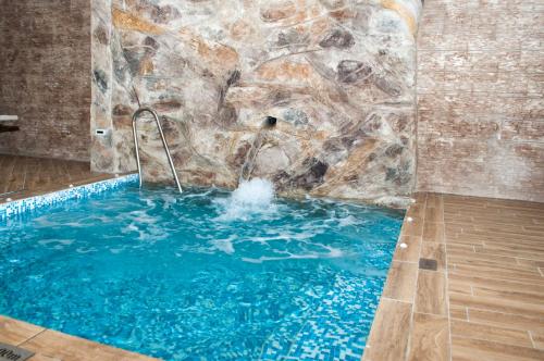 a swimming pool with a stone wall and blue water at Hotel Jaky SPA Complex in Kranevo