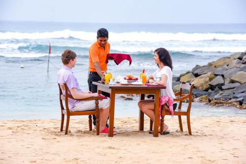 a group of people sitting at a table on the beach at Insight Resort Ahangama - S&S Other Certified in Ahangama