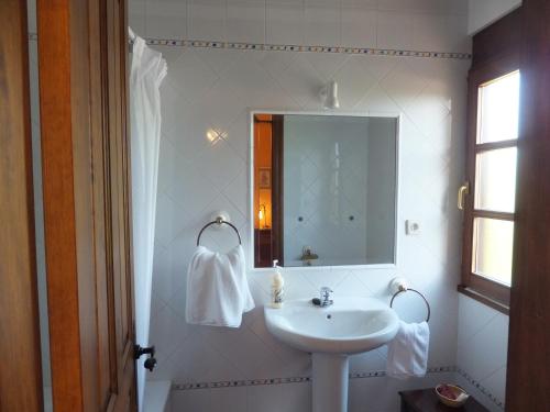 Baño blanco con lavabo y espejo en Posada La Pedriza, en Pontones