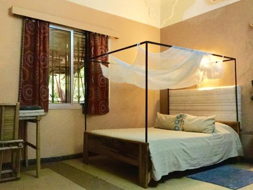 a bedroom with a bed with a canopy at Auberge Djamilla in Bamako