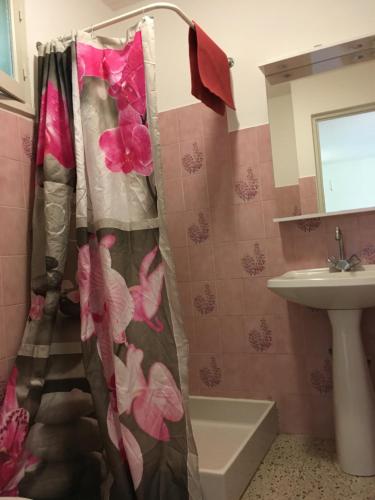 La salle de bains est pourvue d'un rideau de douche avec des fleurs roses. dans l'établissement Thalassa, à Sainte-Lucie de Porto-Vecchio