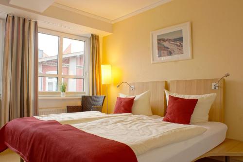 a hotel room with a large bed with red pillows at Baltic Kölln Hotel in Heiligenhafen