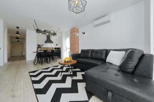 a living room with a black leather couch and a table at Apartments Ivanov in Zadar
