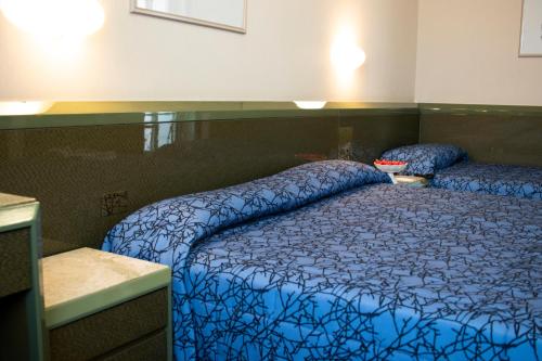 a bedroom with a bed with a blue comforter at Hotel Royal in Fermo