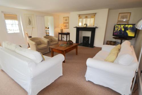 a living room with white couches and a tv at Woodland Cottage in South Molton