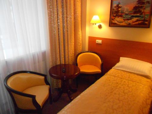 a hotel room with a bed and two chairs and a table at Silvija House in Vilnius