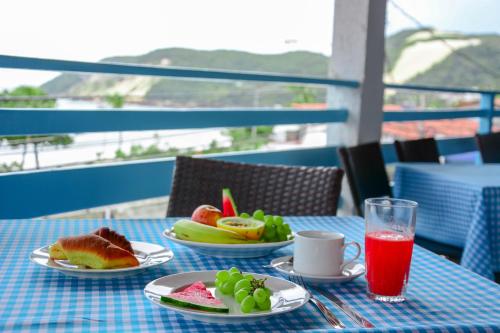 una mesa con platos de comida y un vaso de zumo en Hotel Pousada Maravista, en Natal