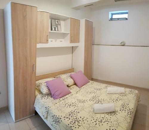 - une petite chambre avec un lit et des oreillers violets dans l'établissement Apartments Dubravka, à Split