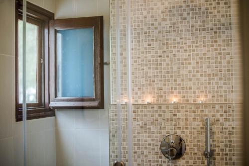 a bathroom with a shower with a mirror and a window at Calderimi Apartments in Fira