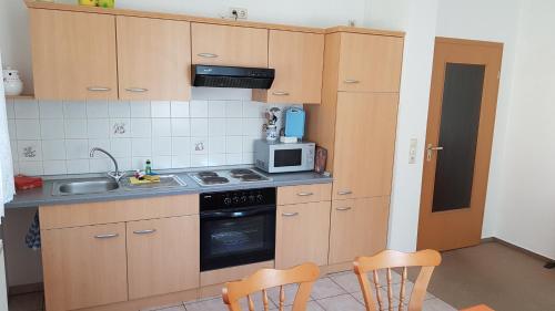 cocina con armarios de madera, fregadero y microondas en Ferienwohnung Richter en Tharandt