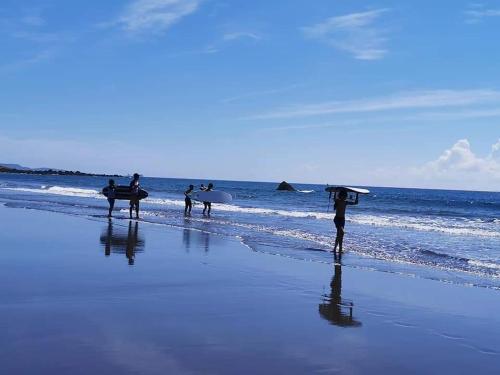 a group of people walking on the beach with surfboards at Ho Hai Yan Homestay in Chenggong