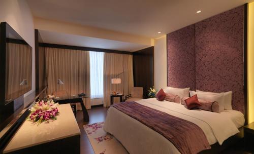 a hotel room with a large bed and a desk at Hotel Royal Orchid Jaipur, Tonk Road in Jaipur