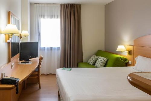 a hotel room with a bed and a desk with a computer at Campanile Madrid Alcalá de Henares in Alcalá de Henares