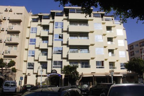 a tall building with cars parked in front of it at New Farah Hotel in Agadir