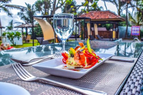 einen Teller mit Essen und ein Glas Wein auf dem Tisch in der Unterkunft Insight Resort Ahangama - S&S Other Certified in Ahangama