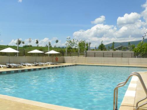 una gran piscina con sillas y sombrillas en Coqueto apartamento Las Margas Golf, en Sabiñánigo