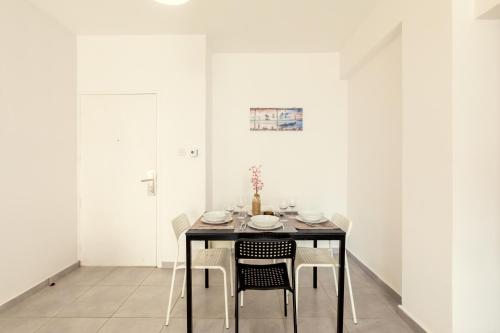 a dining room with a black table and chairs at Savvas City Centre Flat in Larnaka