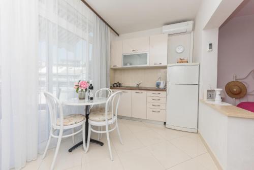 a kitchen with a table and chairs and a refrigerator at Apartmani Antunović Podgora in Podgora