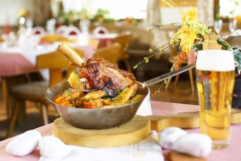 a bowl of food on a table with a glass of beer at Hotel Gasthof Kröll Nationalpark-Card, Bergbahnen, Großglockner, Restaurant mit regionaler Küche in Niedernsill