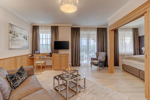 a hotel room with a bed and a living room at Wellness- & Sporthotel Jagdhof in Röhrnbach