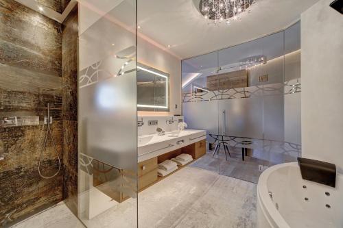 a bathroom with a shower and a sink and a tub at Wellness- & Sporthotel Jagdhof in Röhrnbach