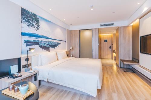 um quarto de hotel com uma cama grande e uma televisão de ecrã plano em Atour Hotel (Hangzhou West Lake Cultural Square) em Hangzhou