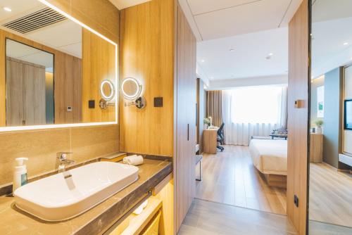ein Bad mit einem Waschbecken und ein Bett in einem Zimmer in der Unterkunft Atour Hotel (Hangzhou West Lake Cultural Square) in Hangzhou