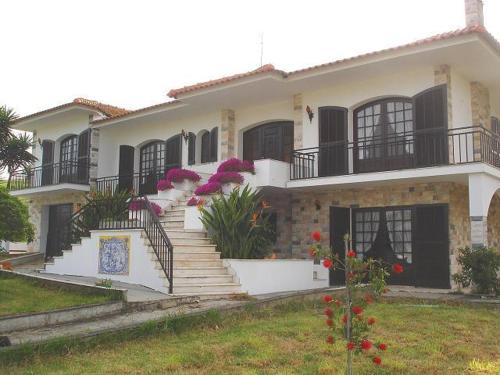 a large white house with stairs and pink flowers at Apartamentos na Casa São Bernardo in Alcobaça