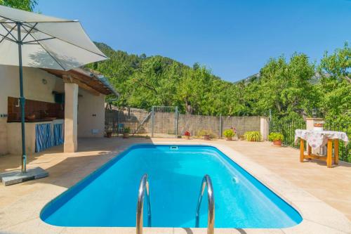 a swimming pool in a backyard with an umbrella at Can Fabiol - Adults Only in Sóller