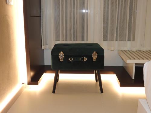 a green suitcase sitting on a chair in a room at Hedoné Design Experience B&B in Agrigento