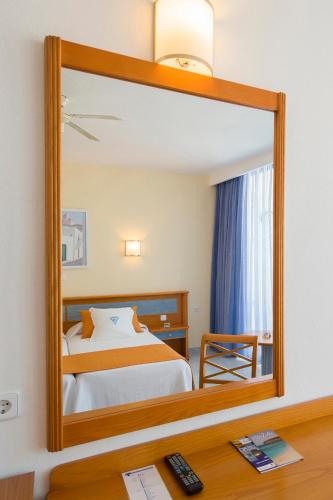 a mirror in a hotel room with a bed at Hotel Osiris Ibiza in San Antonio