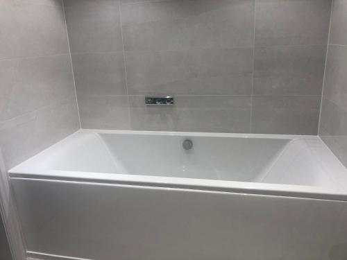 a white bath tub in a white tiled bathroom at Tuppenhurst Barn in Rugeley