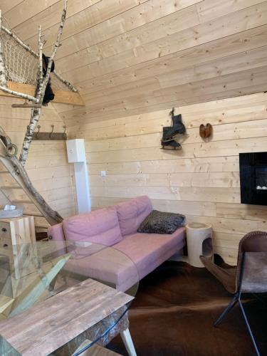 sala de estar con sofá púrpura en una pared de madera en Ecolodge Beauregard, en Treigny