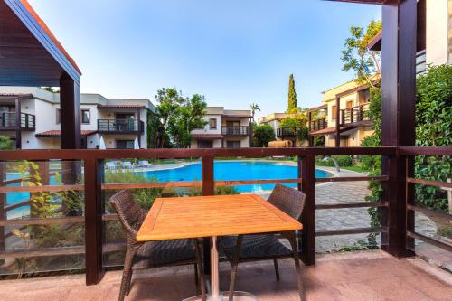 a wooden table and chairs on a balcony with a pool at Faros Bodrum Hotel - Special Category in Golturkbuku