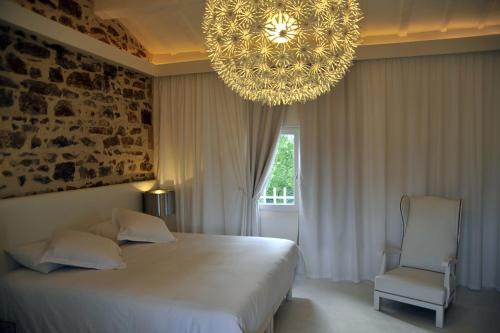 Un dormitorio con una gran cama blanca y una lámpara de araña. en Le Moulin de Saint Laurent, en Saint-Laurent-dʼAigouze