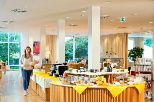 Kobieta przechodząca przez sklep z żółtymi stołami w obiekcie Hotel St. Virgil Salzburg w mieście Salzburg