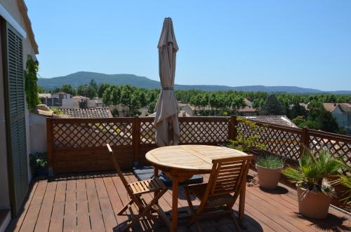 a wooden table and chairs on a balcony with an umbrella at Gite DURANCE in Mallemort