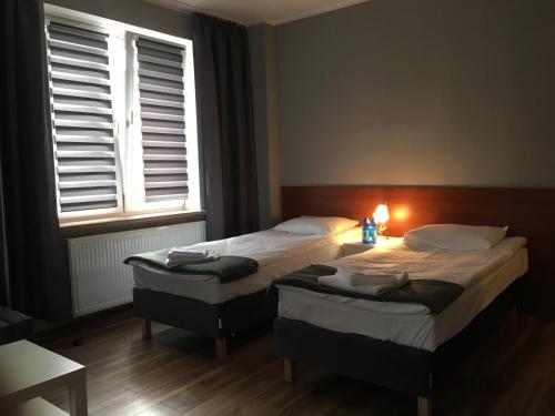 two beds in a room with two windows and a lamp at Apartament Elbląg Centrum in Elblag