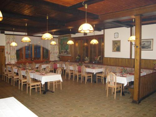 uma sala de jantar com mesas brancas, cadeiras e luzes em Hirscheggerhof em Hirschegg Rein