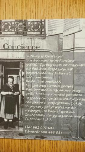 a black and white photo of a woman standing next to a sign at Kwatery w Gołdapi in Gołdap