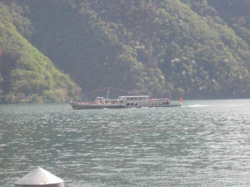 a large boat on the water near a mountain at Caffè del Viaggiatore in Valsolda