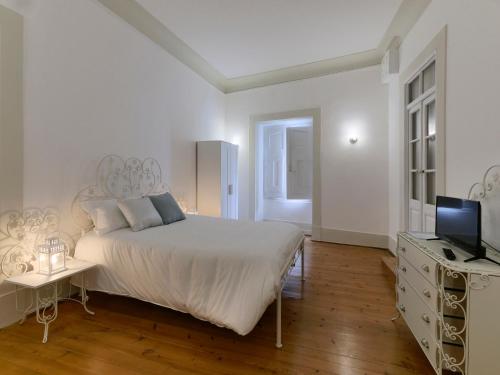a white bedroom with a bed and a television at Casa do Doutor in Portalegre