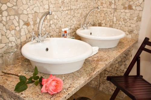 a bathroom with two sinks and a flower on a counter at Die Fonteine Country Guesthouse and Glamping in Oudtshoorn